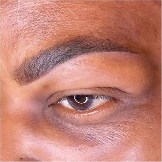 The same eyebrow straight after permanent makeup: a fuller, darker brow on deeper skin.